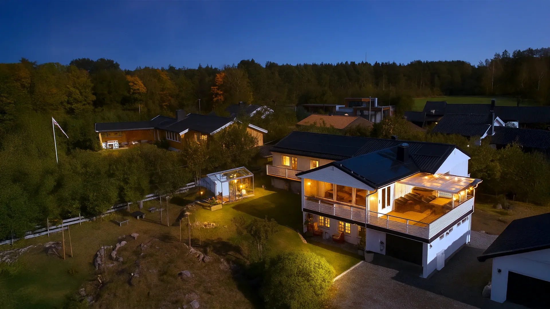 Huis met zonnepanelen, verlicht in de avond, omringd door bomen